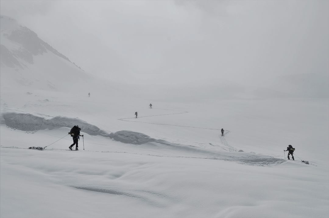 A group of skiers well spaced and navigating avalanche terrain 