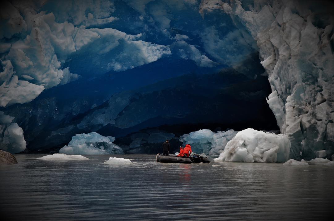 a small zodiac boat close to a glacier tunnel