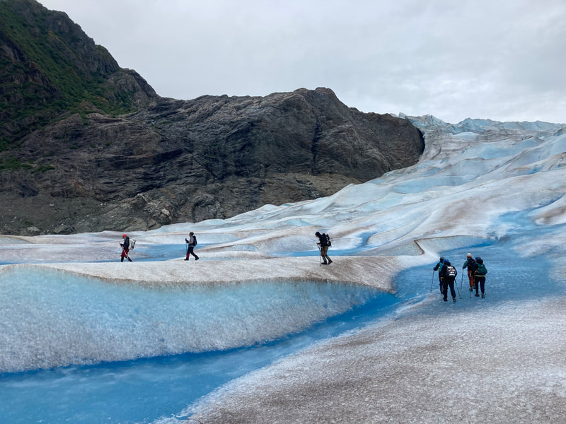 A group of 6 students walking on a glacier