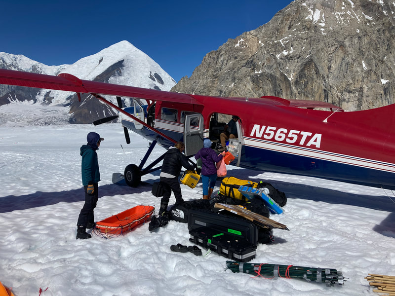 A pile of gear staged outside of a small aircraft on a glacier